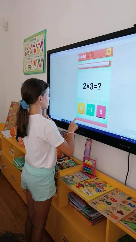 Devojčica vežba tablicu množenja na tač bordu