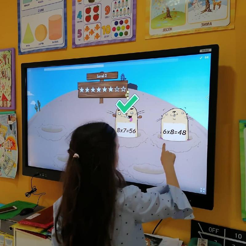 devojčica uči tablicu mnozenja na tač bordu