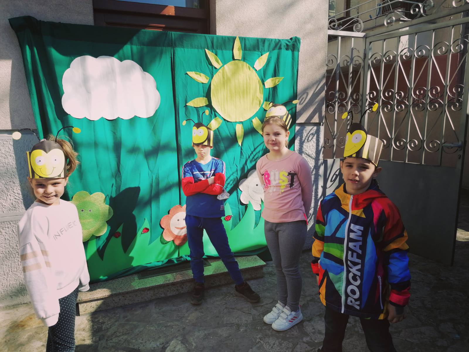 Deca maskirana u pčele ispred improvizovane pozornice koja predstavlja cveće i livadu