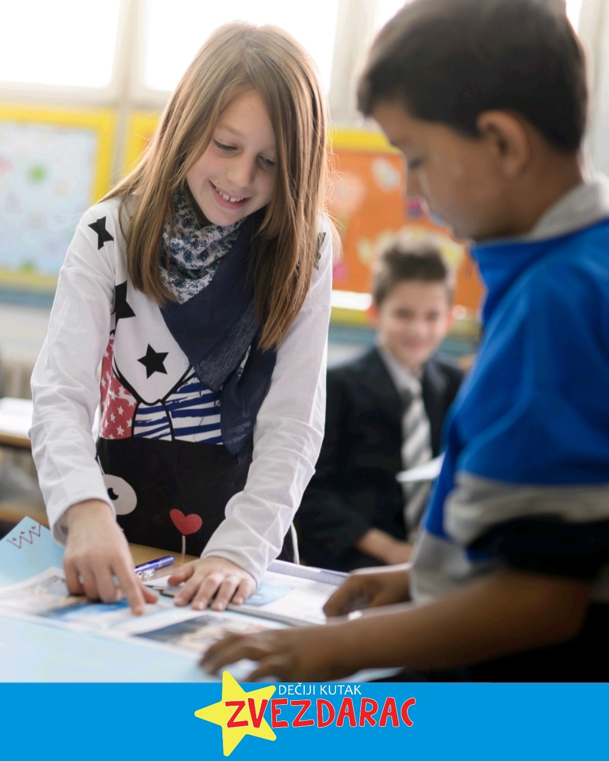 Devojčica pokazuje na sliku u udžbeniku, svome drugaru, u produženom boravku